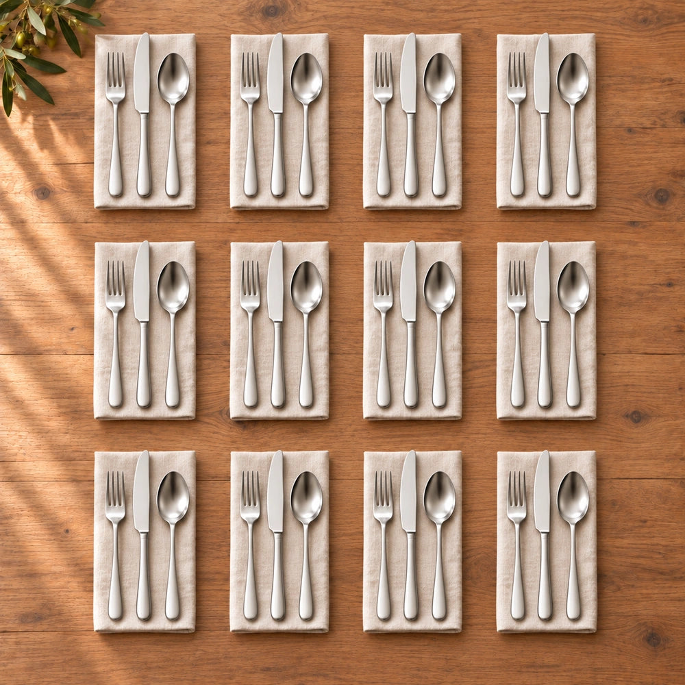 Twaalf groepen zilverkleurig bestek op beige linnen servetten en een houten tafel